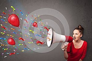 Young girl having fun, shouting into megaphone with balloons