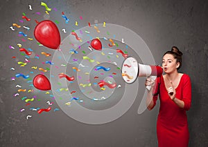 Young girl having fun, shouting into megaphone with balloons