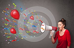 Young girl having fun, shouting into megaphone with balloons