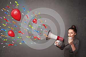 Young girl having fun, shouting into megaphone with balloons