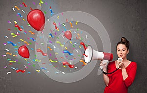 Young girl having fun, shouting into megaphone with balloons