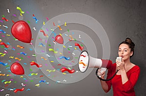 Young girl having fun, shouting into megaphone with balloons