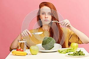 Young girl on healthy food eating dining with broccoli and vegetables