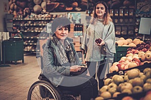 Young girl helping her disabled mothter in wheelchair in a grocery store