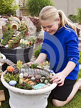 Young girl helping to make fairy garden in a flower pot