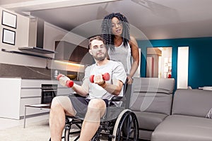 Young girl helps a disabled to rised dumbbells