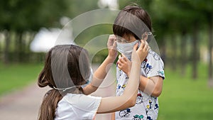 A young girl helps her brother to wear a face mask from the coronavirus covid19