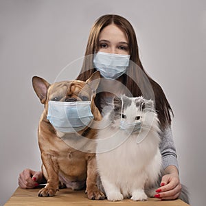 Young girl her cat and dog in medical masks during a pandemic