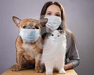 Young girl her cat and dog in medical masks during a pandemic