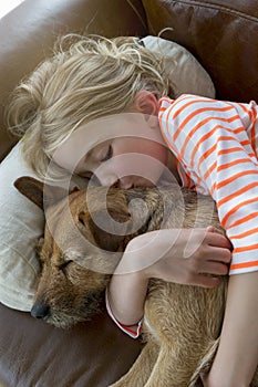 Young girl and her dog cuddling at home