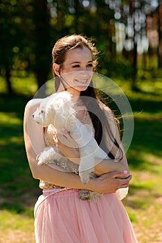 Young girl with her dog. Puppy white dog is running with it`s owner. Concept about friendship, animal and freedom