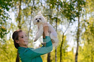 Young girl with her dog. Puppy white dog is running with it`s owner. Concept about friendship, animal and freedom