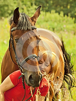 Young girl with her horse in field at summer