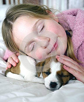 Young girl and her puppy sleeping on a bed