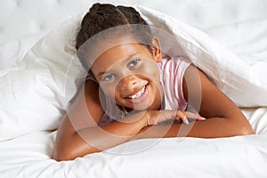 Young Girl Hiding Under Duvet In Bed