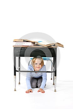 Young girl hiding under a school desk