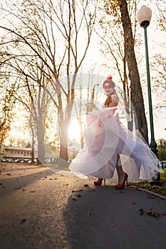 An young girl on a high heels in an autumn park, with a saxophone in her hands