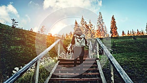 Young girl hiker walking on a stairway with backpack in the mountains landscape at sunset. Lifestyle wanderlust adventure.