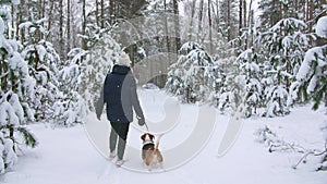 Young girl with his beagle dog are walks through a snowy winter forest. Outdoor walking. Mans best friend. Slow motion