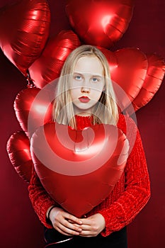 Young girl holding balloons red heart. Valentines people and Valentine`s day concept