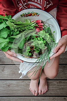 Young girl holding a bowl with the garden harvest