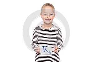 Young girl holding a card with letter K. Speech therapy concept on white background. Correct pronounciation and articulation.