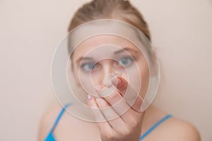 Young girl holding a contact lens on her finger