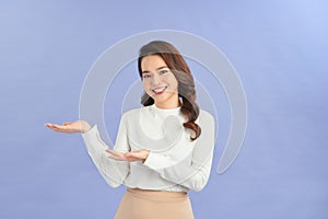 Young girl holding copyspace imaginary on the palm to insert an ad on purple background