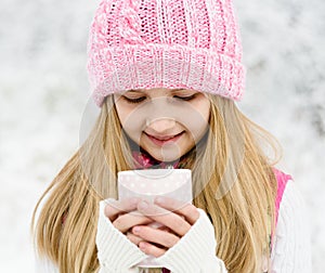 A young girl holding a cup of hot drink and smiling