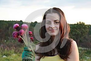 A young girl holding a flower - milk thistle, bouquet