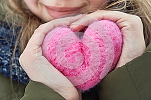 Young girl holding in hands a pink woolen heart
