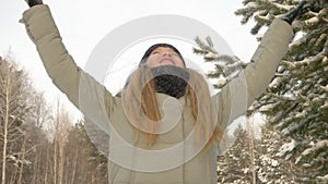 Young girl holding in hands snow. Girl blows and throws up snow in winter forest