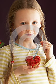 Young Girl Holding Heart Shaped Cookie In Studio