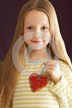 Young Girl Holding Heart Shaped Cookie In Studio