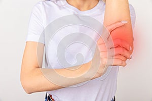 Young girl holding her elbow joint over white background. Pain and inflammation in the elbow