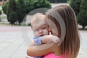 Young girl holding her newborn brother in her arms and looking at him with tenderness