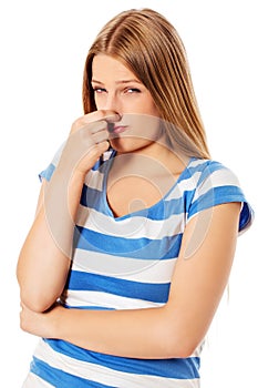 Young girl holding her nose smelling something stinking.