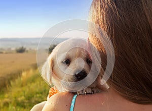 Young girl holding her puppy dog on her shoulder - close up