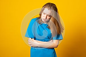 Young girl holding her stomach and frowns. Teenage girl has a stomach ache. Female writhes in pain. Health concept