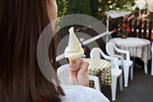 A young girl holding ice cream in a patisserie garden with chair