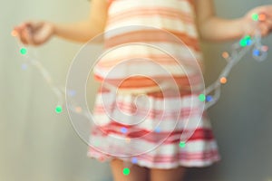 Young girl holding out of focus Christmas lights. Christmas holiday background