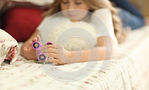 Young girl holding popular fidget spinner toy - closeup shot. at home on bed