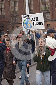 Young girl holding a sign reading Save Our Future with a cartoon drawing of the Earth.
