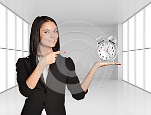 Young girl holding silver alarm clock on hand