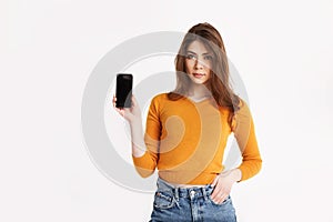 A young girl is holding a smartphone. Portrait of a girl with a phone in her hands on a light background with space for text