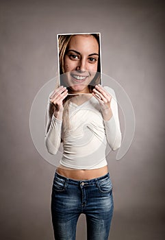Young girl holding a smily portrait in front of her face