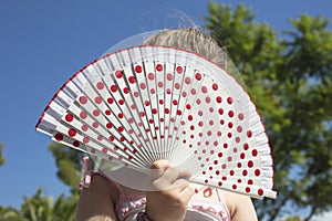 Young girl holding a spanish fan with red dots outdoors