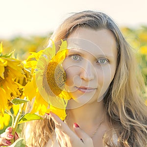 Young girl holding sunflowers outdoor shot. Portrait of beautiful blonde girl with bright yellow sunflower in hands on sunflowers