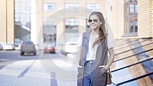 A young girl is holding sunglasses outside hands in the pockets