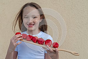 Young girl holding two fresh juicy strawberries in hands. Summer, childhood lifestyle concept